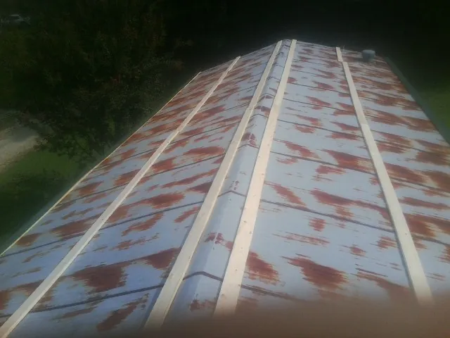 Rusted metal roof panels with new wood purlins before replacement — Storm Damage Roof Repair in Mumford by Roofing Brothers