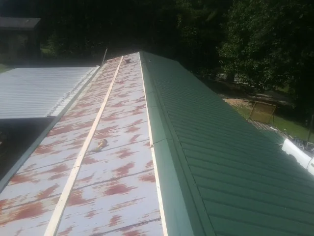 Old rusted panels beside newly installed green metal roofing — Wind Damage Roof Repair by Roofing Brothers in Mumford