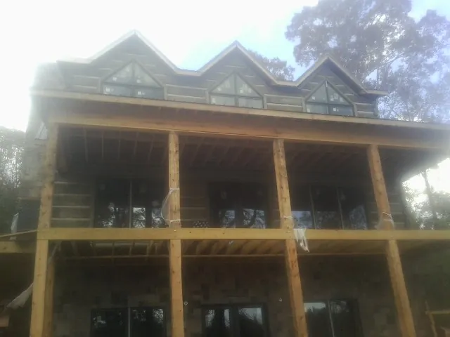 Dormers and porch framing on a large log home under construction — Roof Coating work by our crew in Mumford