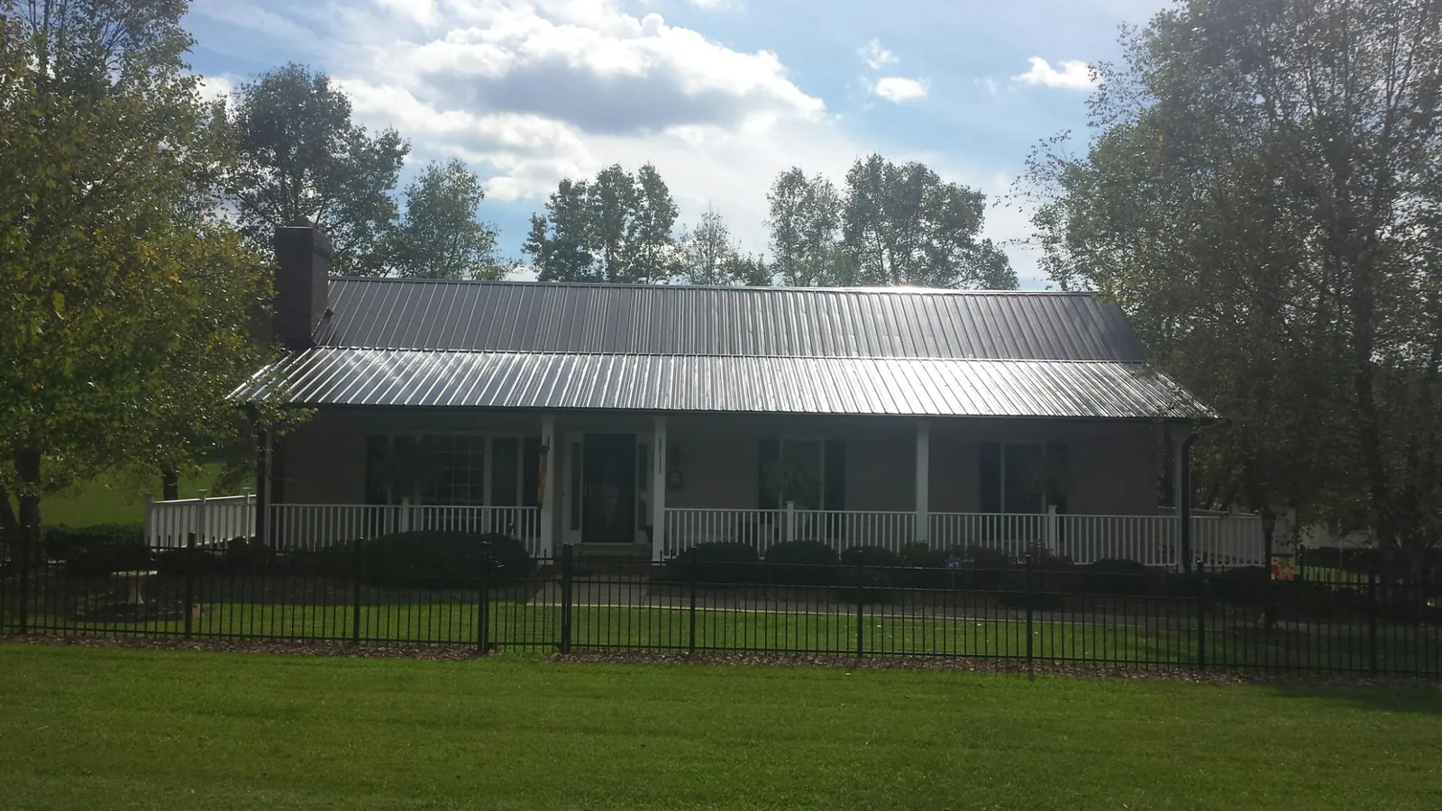 Gray metal roof on a brick ranch with a full width front porch — Gutter Guard Installation work by our crew in Mumford