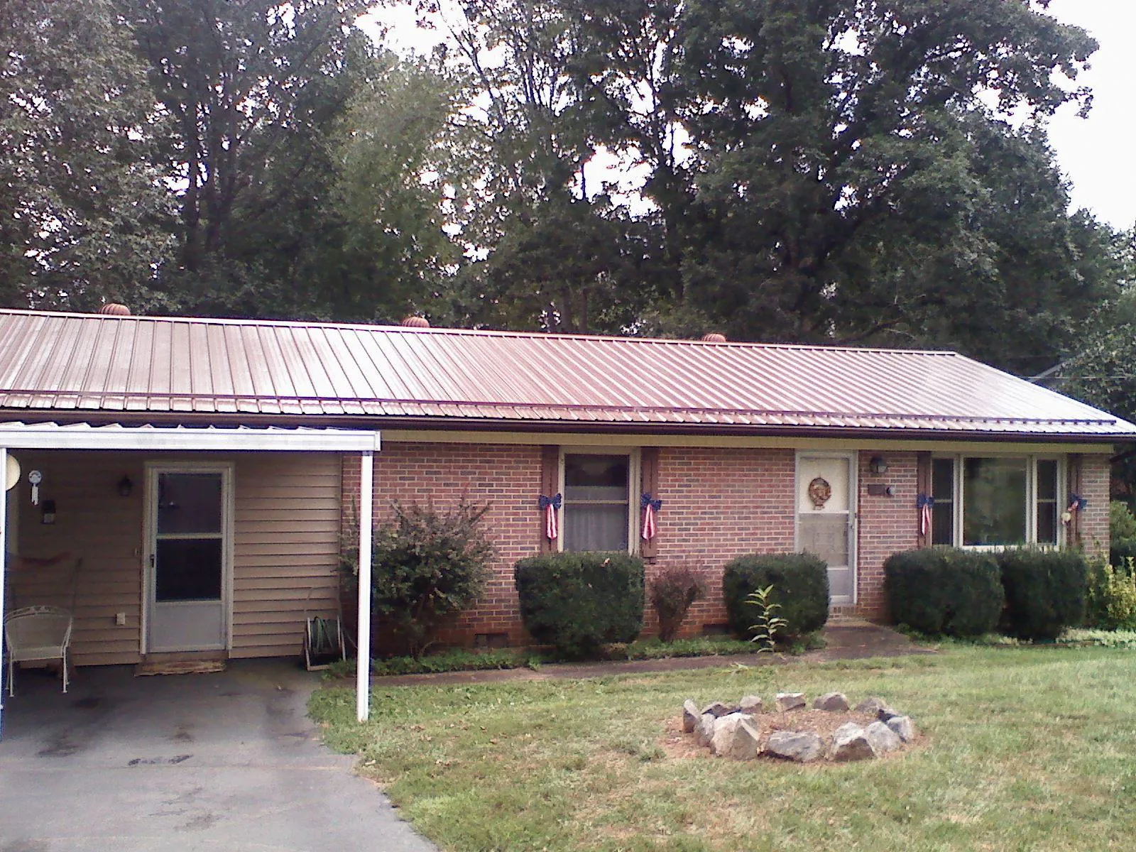 Bronze metal roof and carport on a brick ranch home — Roof Repair work by our crew in Mumford