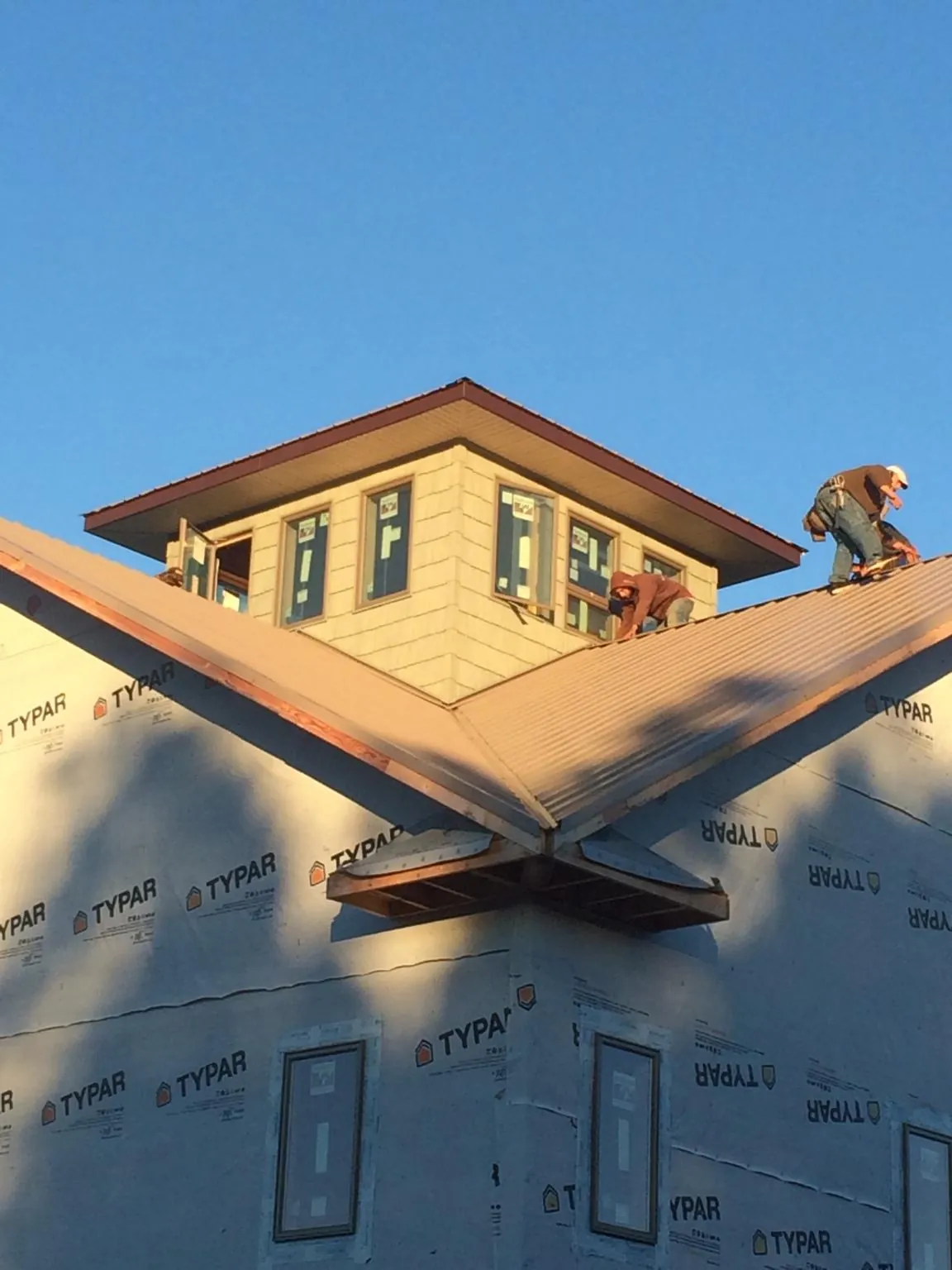 Roofers working around a rooftop cupola on a new metal roof at sunset — Roof Waterproofing in Mumford by Roofing Brothers